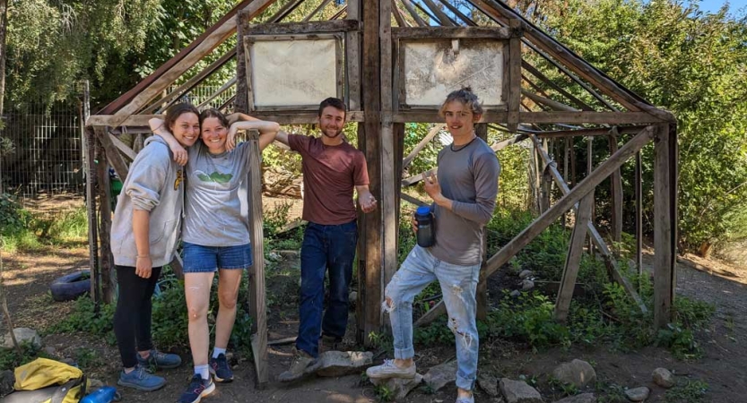 A group of people pose for a photo in front of small wooden structure